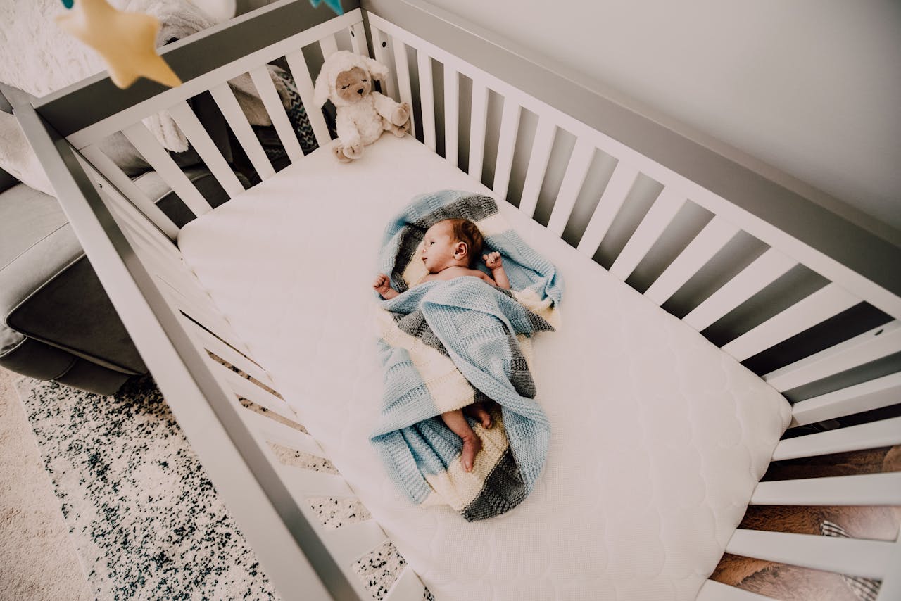about-us A peaceful baby wrapped in a blanket sleeps in a cozy crib, creating a serene nursery atmosphere.